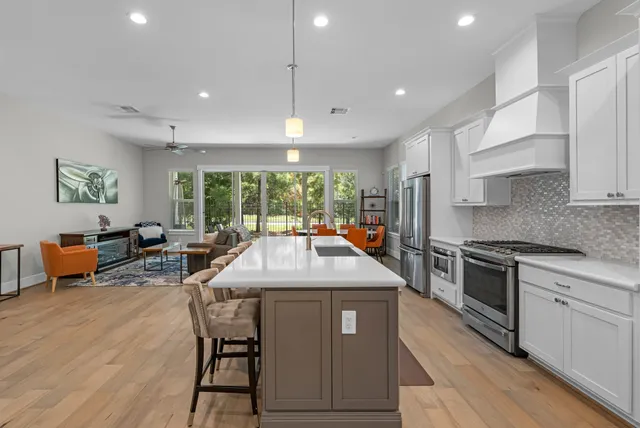 a kitchen with stainless steel appliances granite countertop a stove a sink dishwasher and a refrigerator with wooden floor