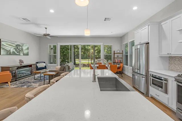 a living room with furniture a large window and stainless steel appliances