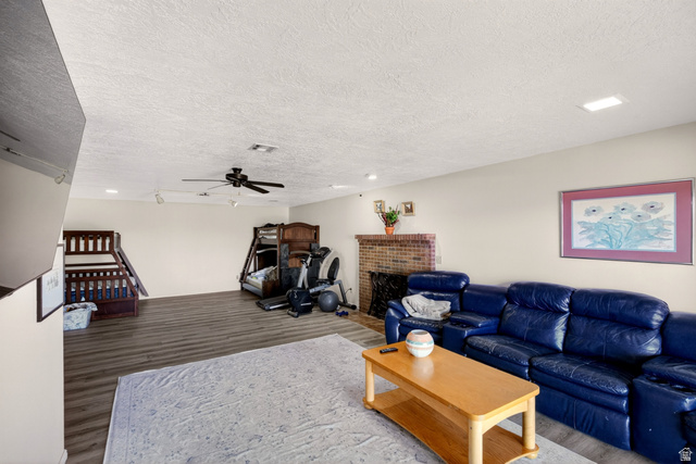 161 West 950 South, Unit Q1 St. George, UT 84770 - Photo 23 of 37 Living area with wood finished floors, a brick fireplace, a textured ceiling, and a ceiling fan