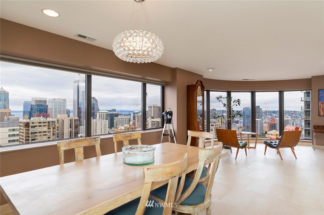 1301 Spring Street, Unit 18J Seattle, WA 98104 - Photo 6 of 25 a dining room with furniture large windows and a chandelier