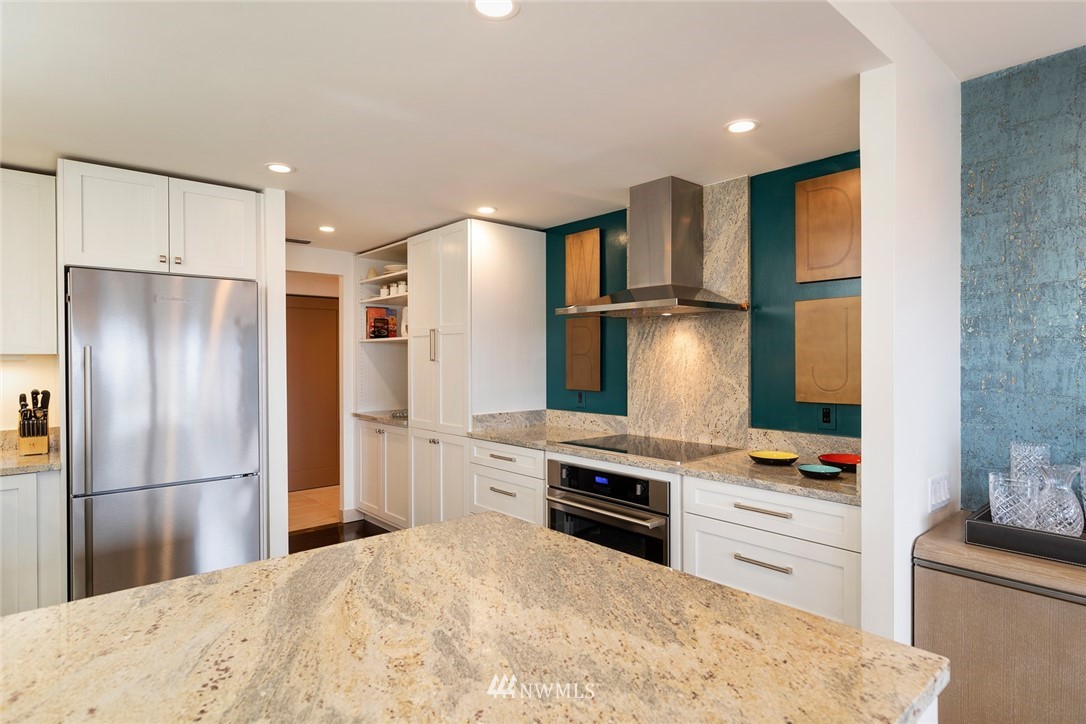 1301 Spring Street, Unit 18J Seattle, WA 98104 - Photo 9 of 25 a kitchen with stainless steel appliances kitchen island granite countertop a refrigerator stove and microwave