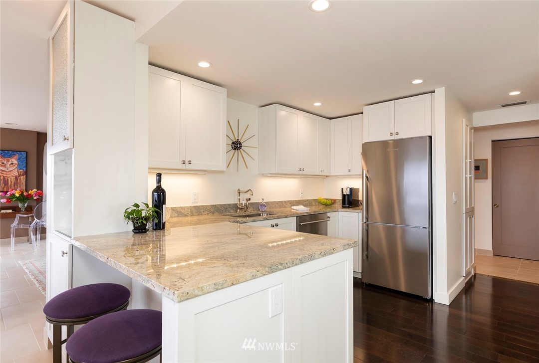 1301 Spring Street, Unit 18J Seattle, WA 98104 - Photo 10 of 25 a kitchen with stainless steel appliances granite countertop a sink refrigerator and cabinets