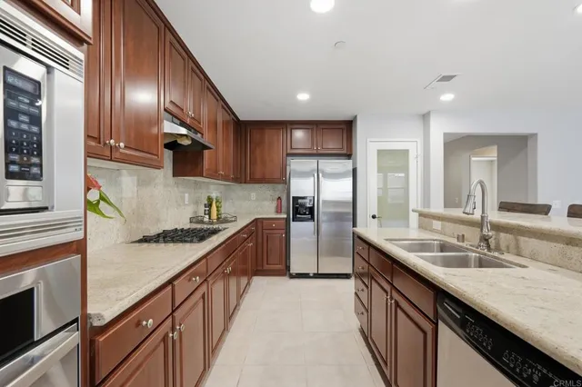 a kitchen with stainless steel appliances granite countertop lots of counter top space a sink wooden cabinets and granite counter tops