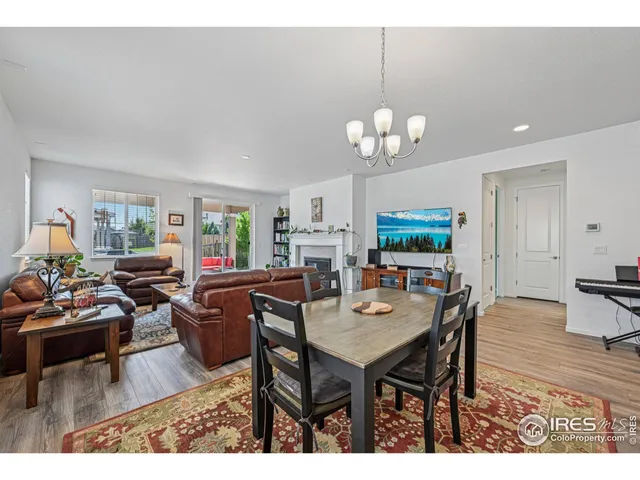 a kitchen with granite countertop a stove a sink dishwasher a dining table and chairs with wooden floor