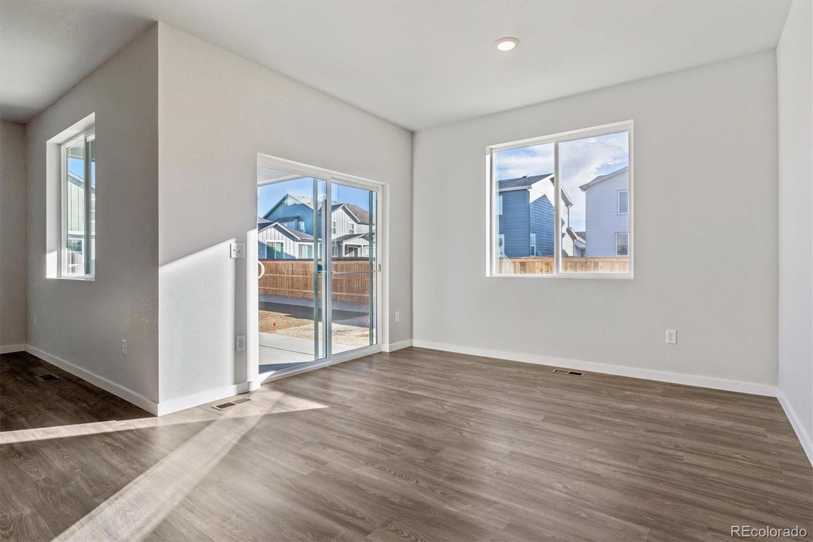 1446 Farmstead Street Brighton, CO 80601 - Photo 11 of 26 an empty room with wooden floor and windows
