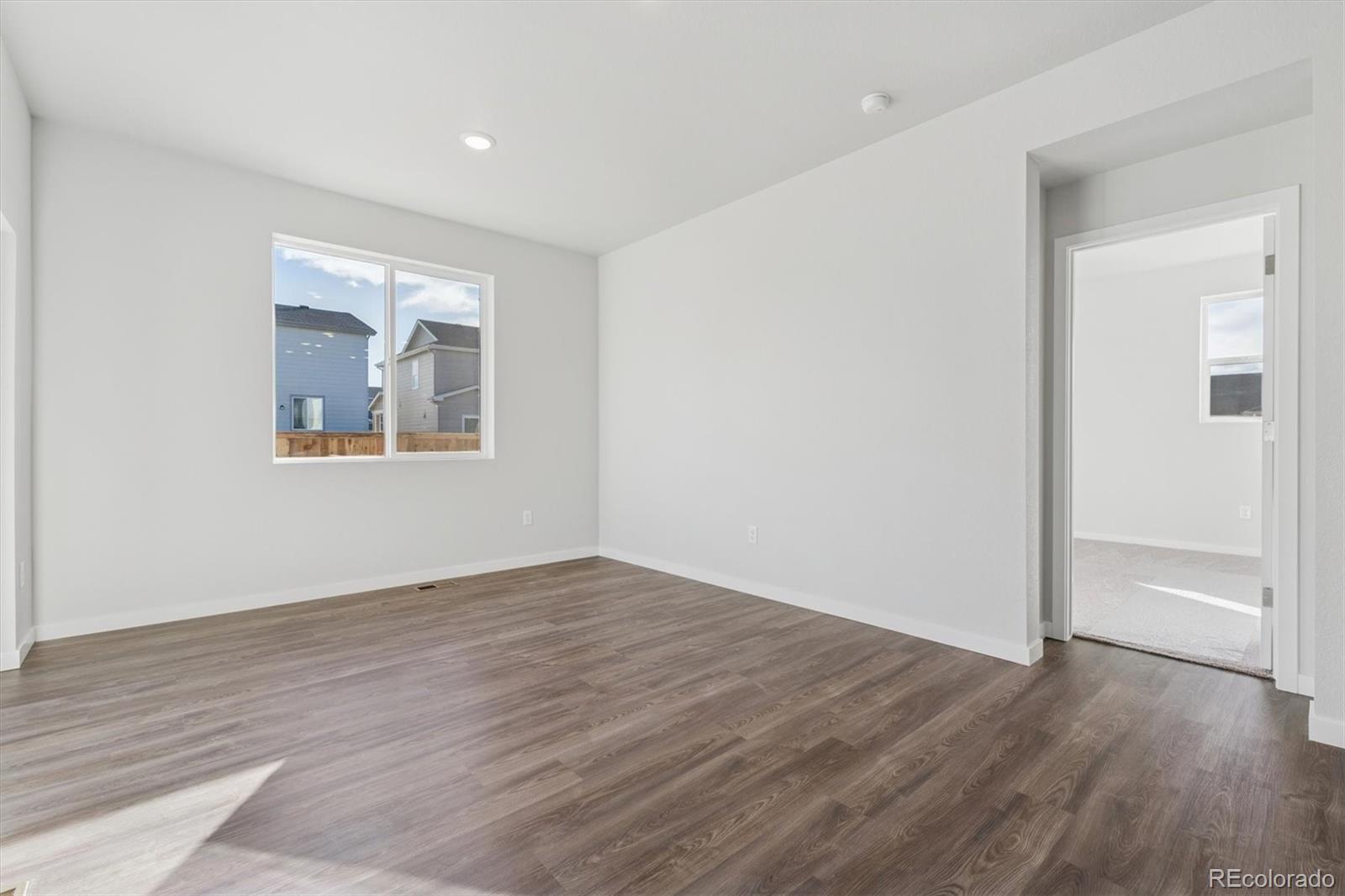 1446 Farmstead Street Brighton, CO 80601 - Photo 14 of 26 a view of an empty room with wooden floor and a window