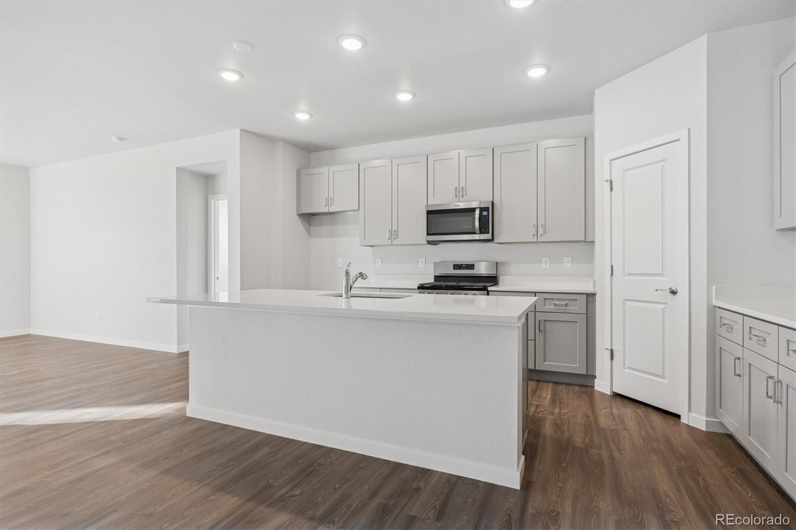 1446 Farmstead Street Brighton, CO 80601 - Photo 2 of 26 a kitchen with kitchen island white cabinets and stainless steel appliances