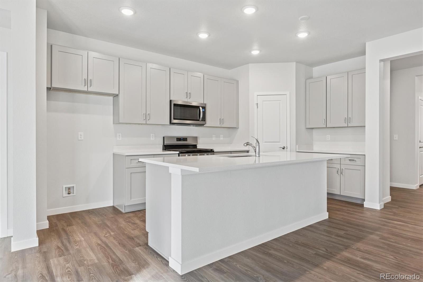 1446 Farmstead Street Brighton, CO 80601 - Photo 3 of 26 a kitchen with cabinets stainless steel appliances and wooden floor