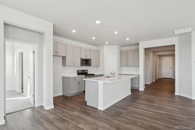 a large kitchen with a center island wooden floor stainless steel appliances and cabinets