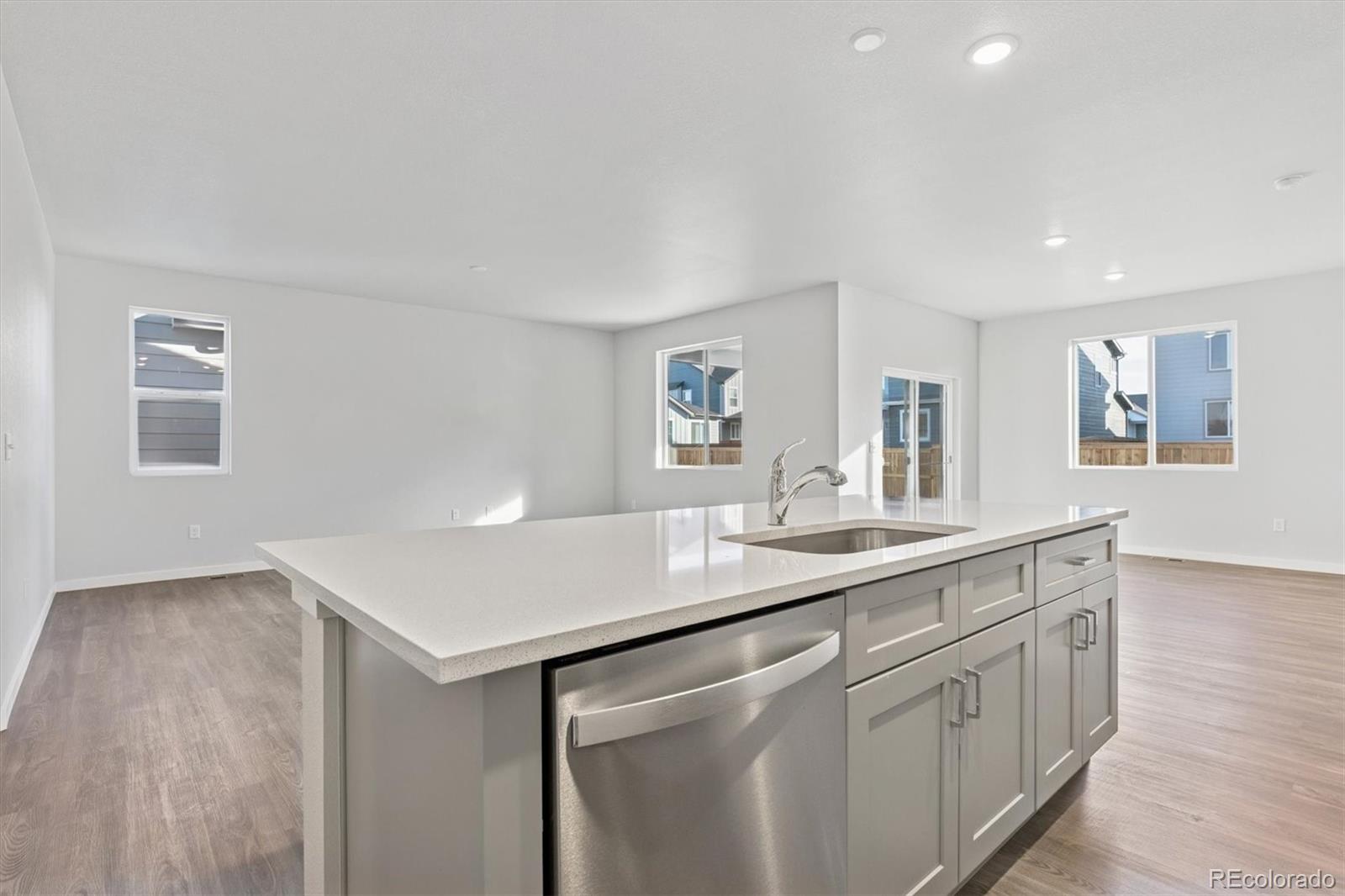1446 Farmstead Street Brighton, CO 80601 - Photo 4 of 26 a kitchen with a sink dishwasher and a refrigerator with wooden floor