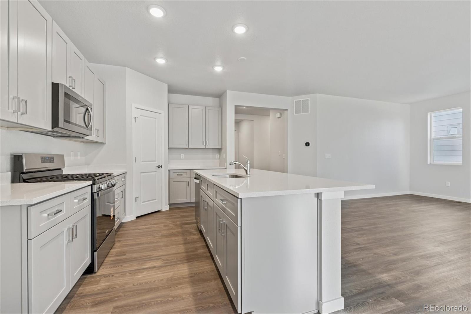 1446 Farmstead Street Brighton, CO 80601 - Photo 5 of 26 a kitchen with a sink and wooden floor