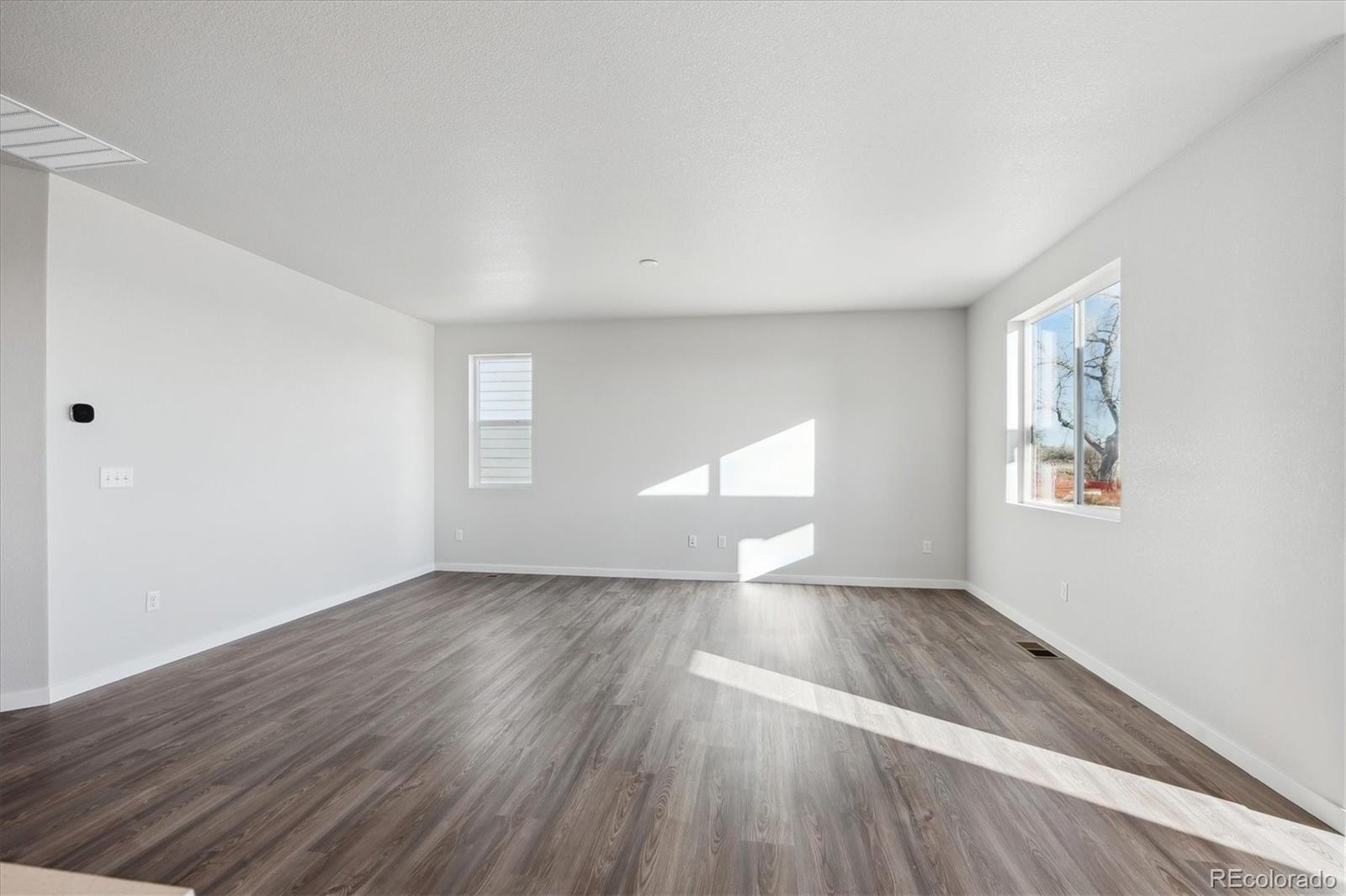 1446 Farmstead Street Brighton, CO 80601 - Photo 9 of 24 an empty room with wooden floor and windows