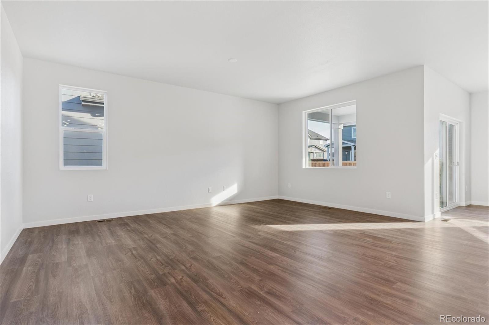 1446 Farmstead Street Brighton, CO 80601 - Photo 10 of 26 an empty room with wooden floor and windows