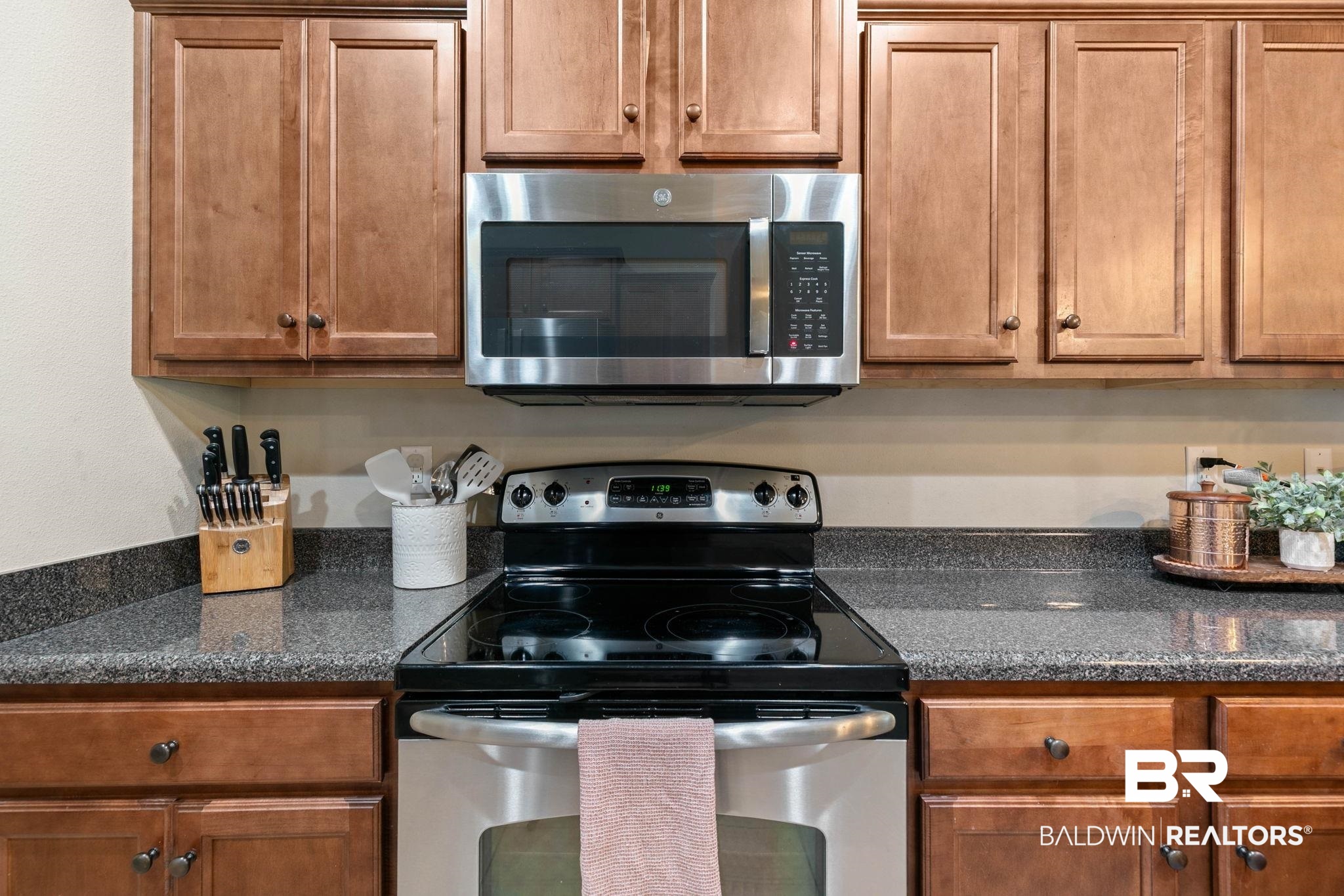 2216 Livingstone Court Mobile, AL 36695 - Photo 17 of 62 Kitchen featuring wood cabinetry, stainless steel microwave, black electric range, and speckled countertops