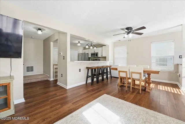 a view of a dining room and livingroom with furniture wooden floor a chandelier