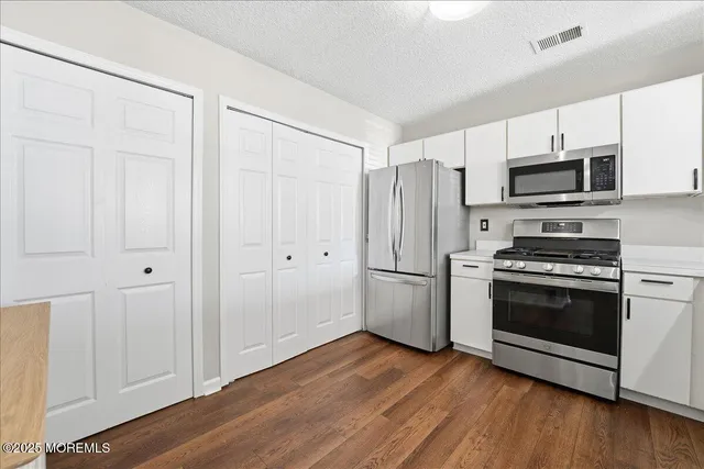 a kitchen with stainless steel appliances wooden floor and white cabinets
