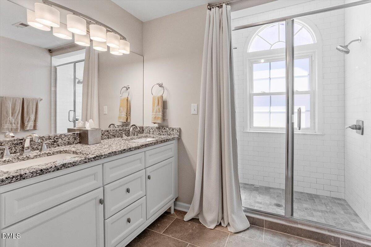8321 Hempshire Place, Unit 103 Raleigh, NC 27613 - Photo 21 of 25 a bathroom with a double vanity sink and a mirror