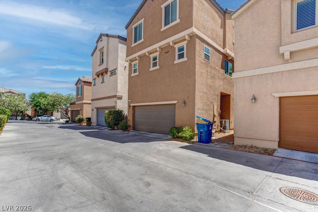 7724 Vibrant Thread Court Las Vegas, NV 89149 - Photo 41 of 43 A quiet residential street showcases uniform multi-story townhomes with integrated garages under a clear sky.
