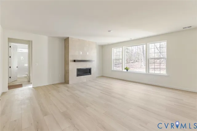 an empty room with windows and fireplace