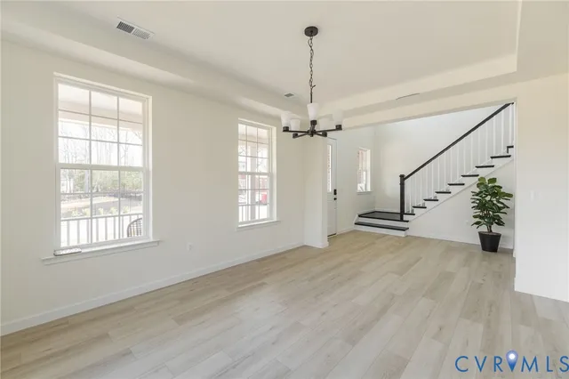 a view of an empty room with wooden floor windows and a chandelier