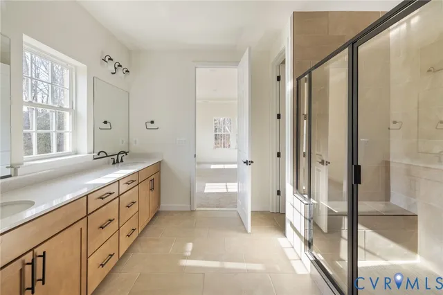 a spacious bathroom with a double vanity sink a mirror and a shower