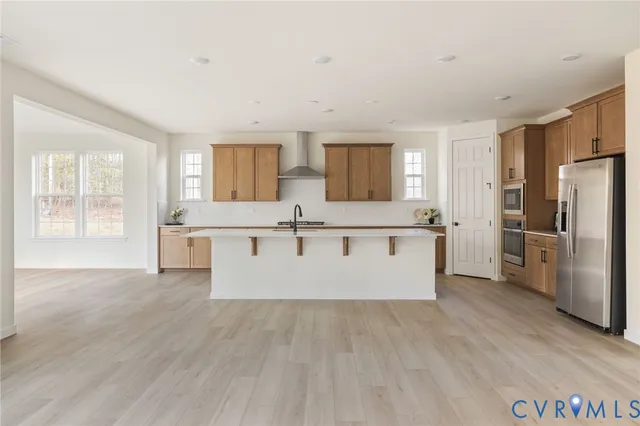 a large kitchen with a center island wooden floor and stainless steel appliances