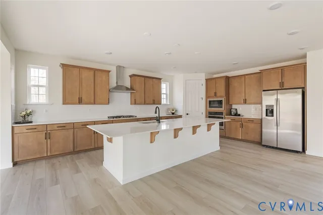 a large white kitchen with stainless steel appliances granite countertop a stove a sink dishwasher and a refrigerator with wooden floor