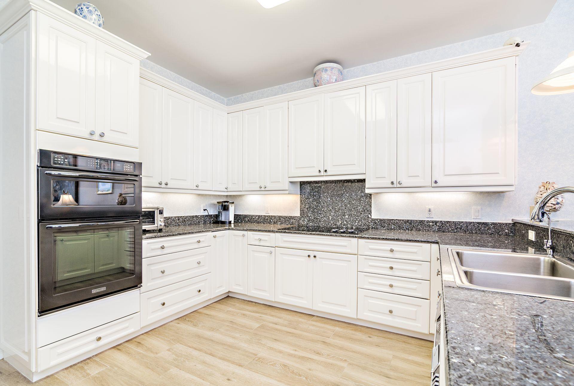 16757 Port Royal Circle Jupiter, FL 33477 - Photo 17 of 65 a kitchen with granite countertop a sink stove and cabinets