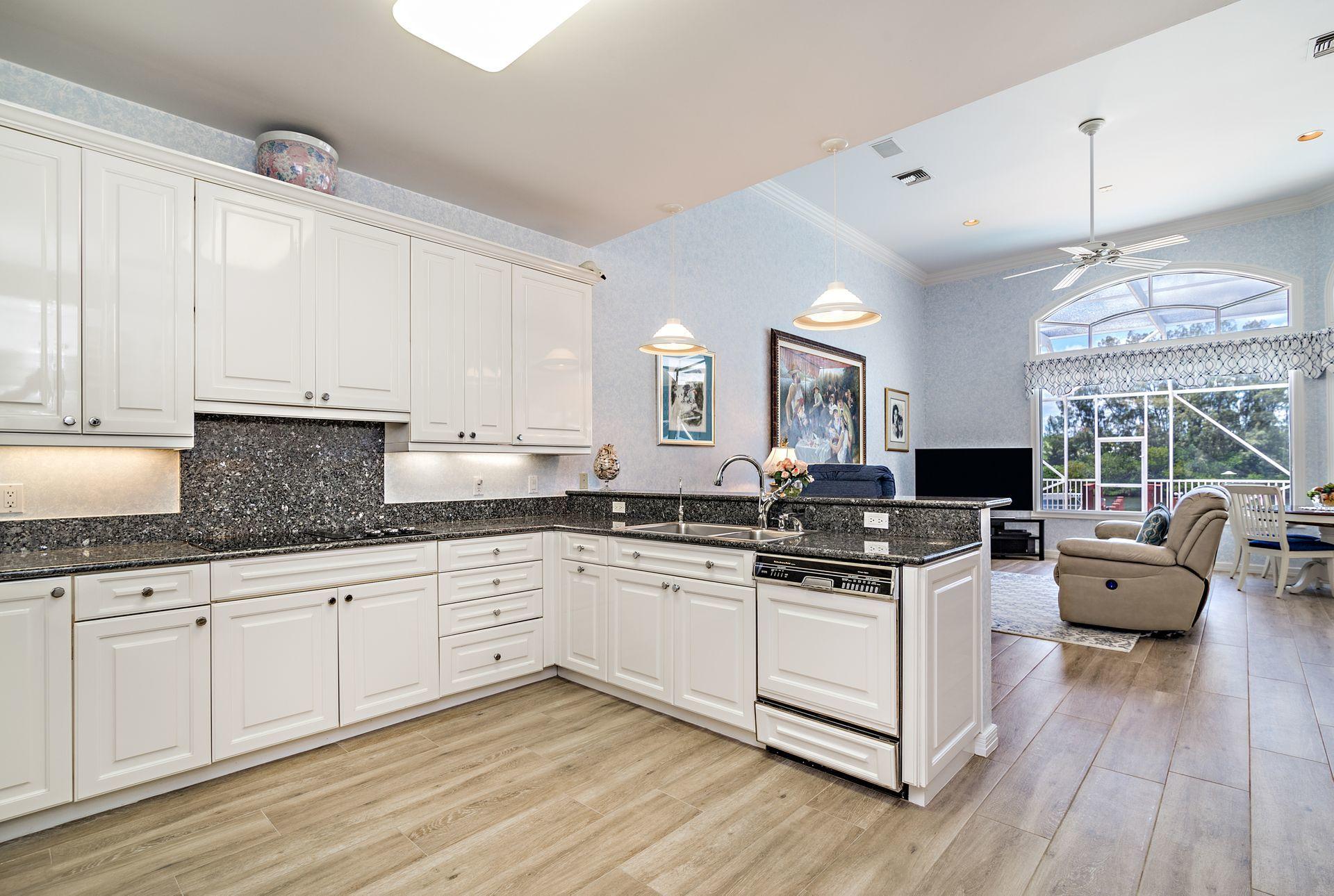 16757 Port Royal Circle Jupiter, FL 33477 - Photo 18 of 65 a kitchen with granite countertop a sink cabinets and wooden floor