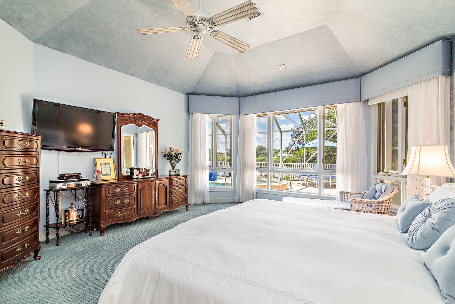 16757 Port Royal Circle Jupiter, FL 33477 - Photo 24 of 65 a large bedroom with a large bed and flat tv