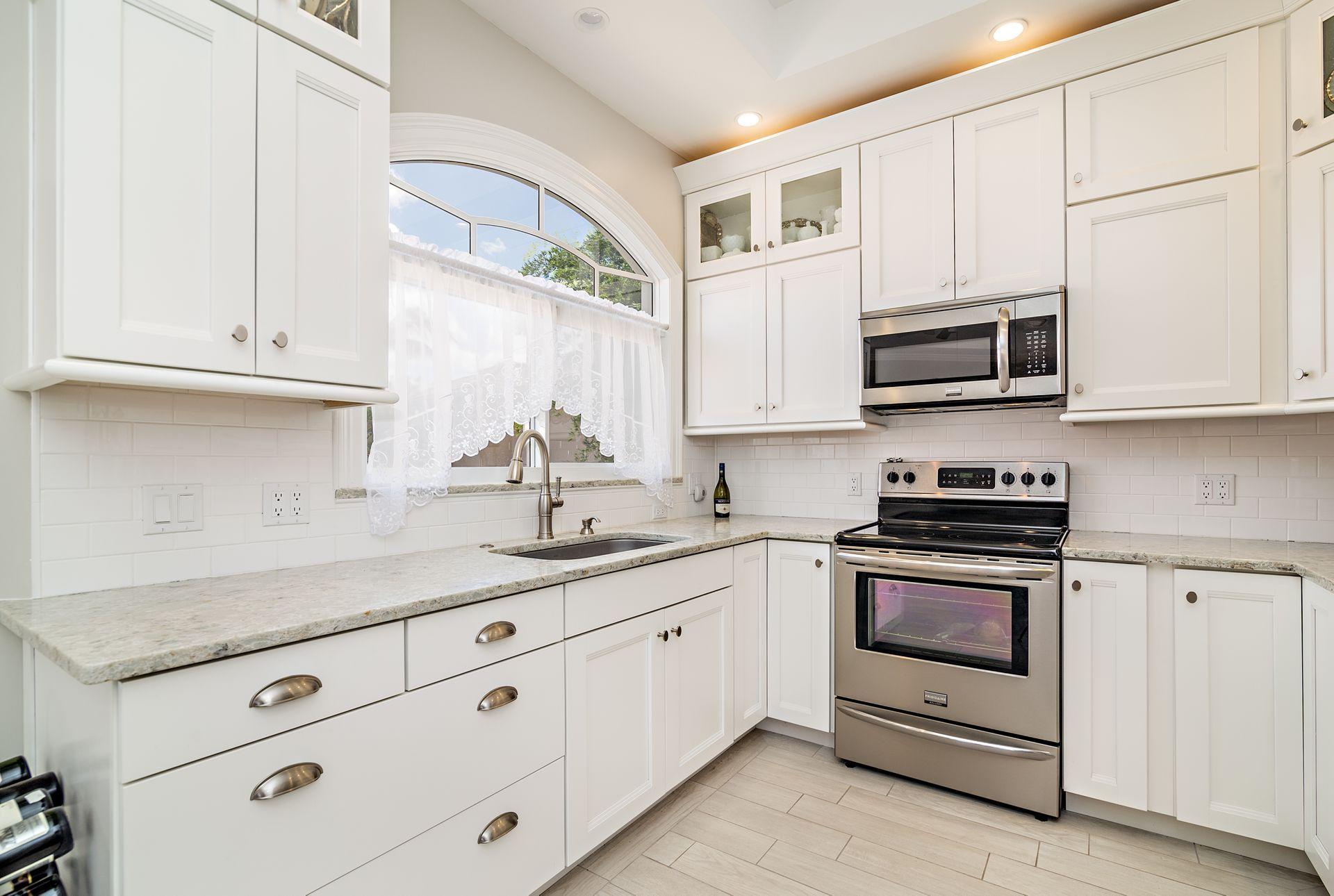 16757 Port Royal Circle Jupiter, FL 33477 - Photo 37 of 65 a kitchen with granite countertop white cabinets white stainless steel appliances and a sink