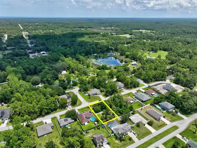 an aerial view of residential houses with outdoor space and trees