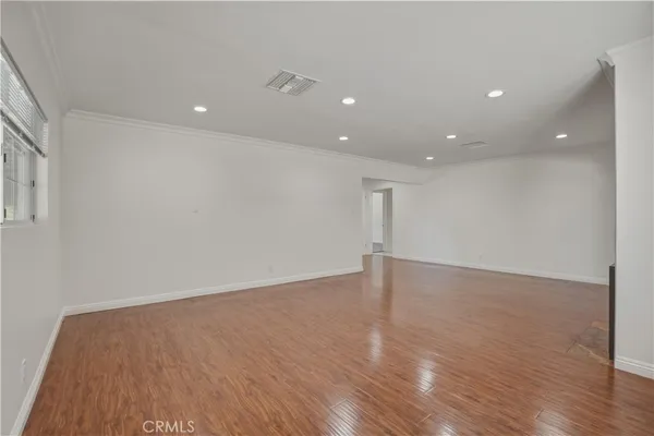 a view of an empty room with wooden floor and closet