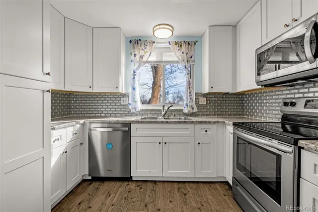 a kitchen with granite countertop white cabinets white stainless steel appliances and a sink