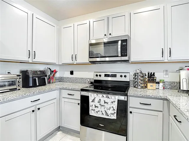 a kitchen with granite countertop white cabinets and stainless steel appliances