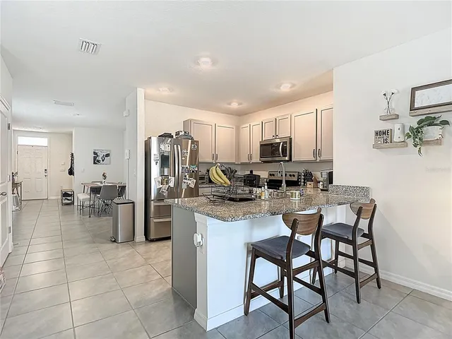 a kitchen with refrigerator and chairs