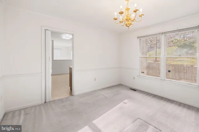 an empty room with windows and chandelier fan