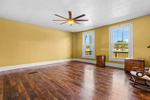 a view of an empty room with window and wooden floor