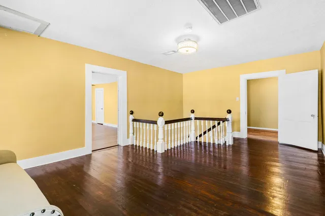 a view of an empty room with window and wooden floor