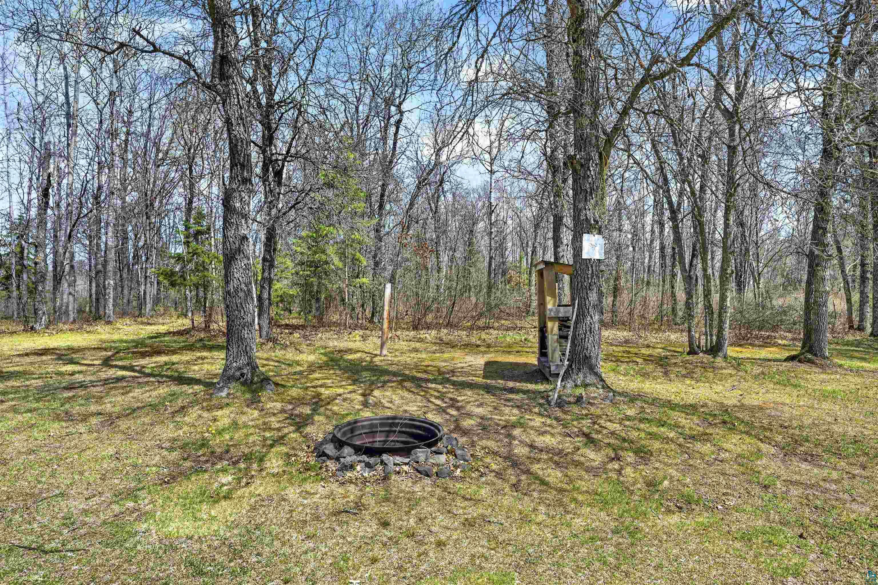 12235 East Crooked Lake Road Gordon, WI 54838 - Photo 42 of 48 Outdoor fire pit surrounded by natural stone, mature trees, and a wooded backdrop