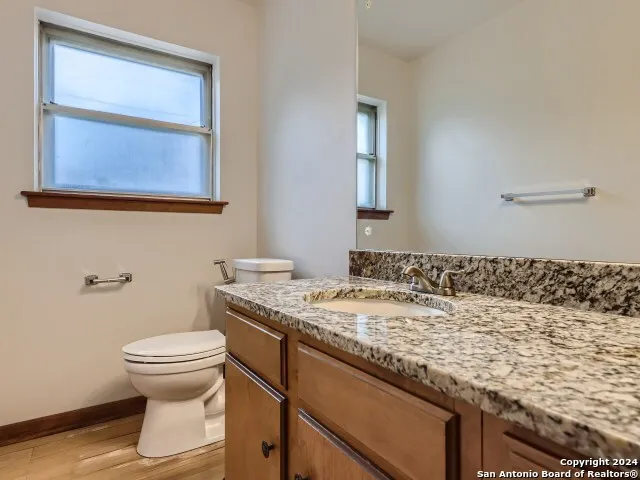 a bathroom with a granite countertop sink toilet and mirror
