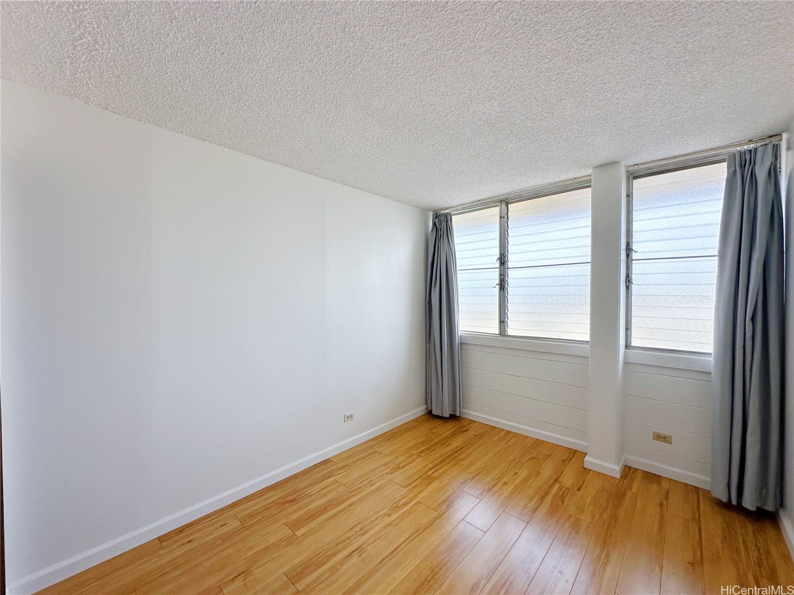 2977 Ala Ilima Street, Unit 809 Honolulu, HI 96818 - Photo 6 of 14 an empty room with wooden floor and windows