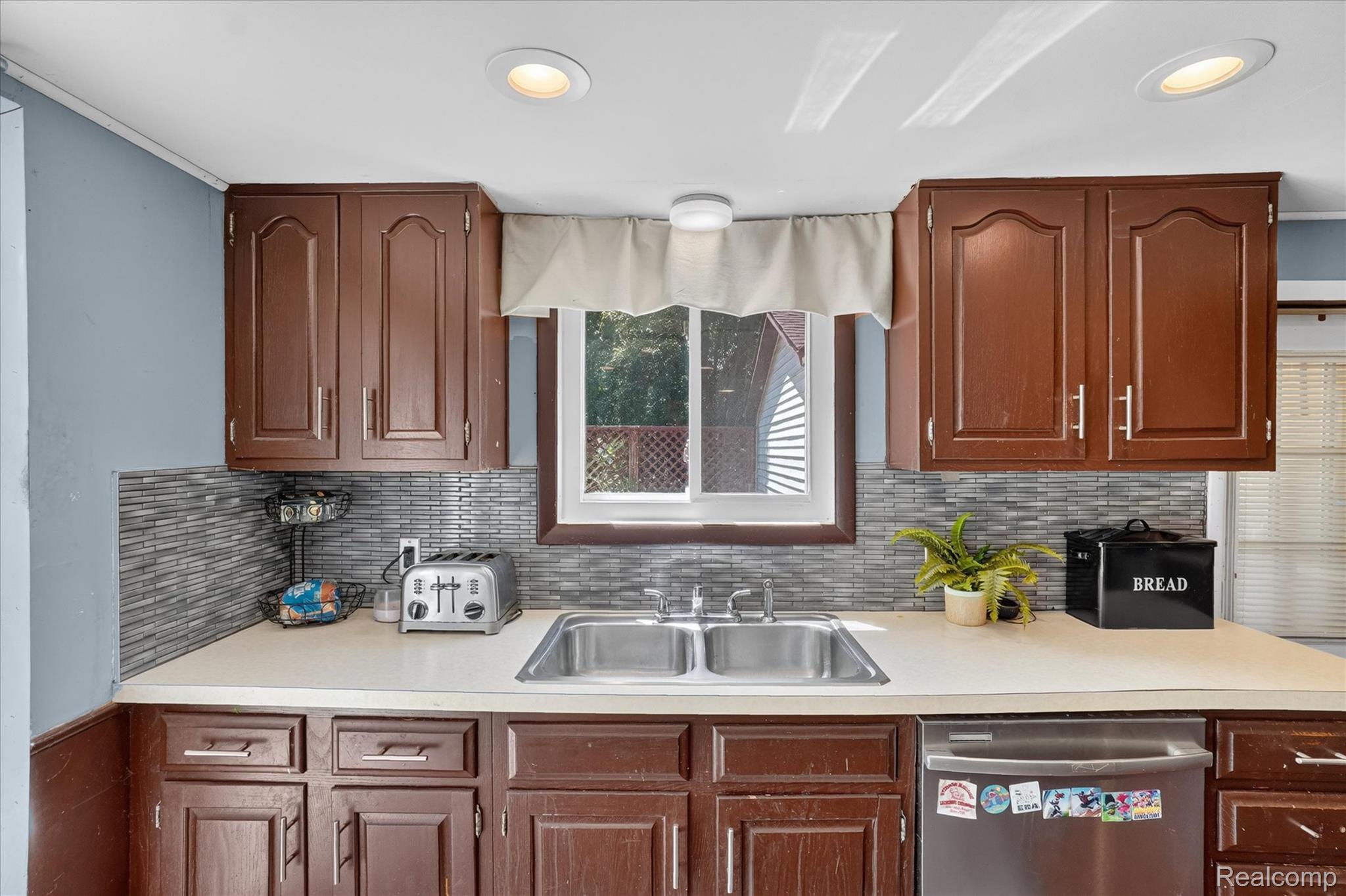 508 Deland Road Flushing, MI 48433 - Photo 14 of 38 Kitchen featuring wood-finish cabinetry, light-toned countertops, and a dual-basin stainless steel sink