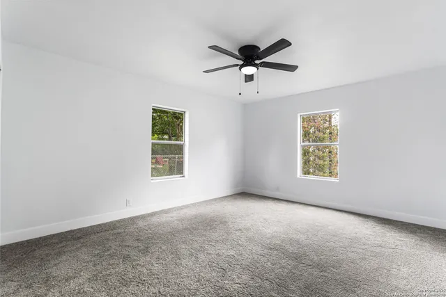 an empty room with window and ceiling fan