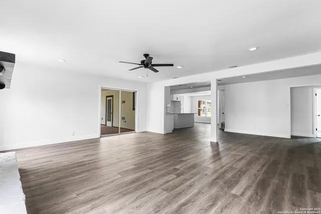 a view of empty room with wooden floor and ceiling fan
