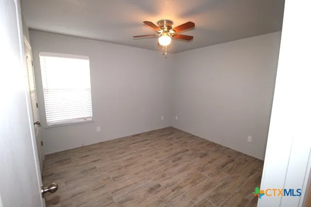 an empty room with a window and a chandelier fan