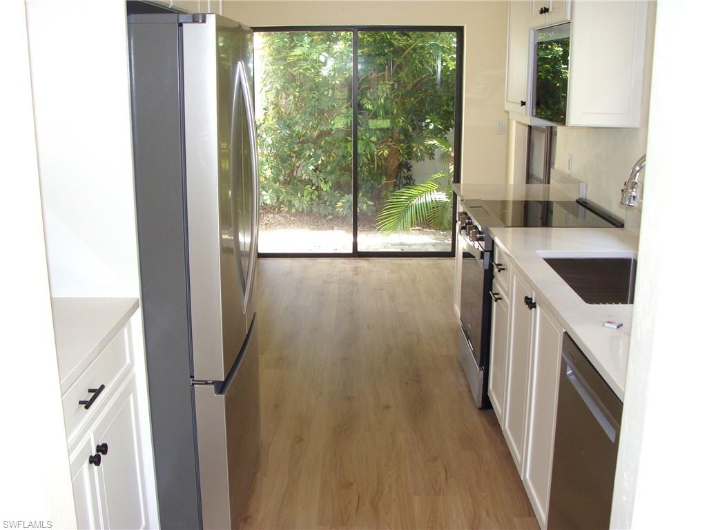 857 Reef Point Circle Naples, FL 34108 - Photo 5 of 27 a kitchen with a sink a refrigerator a washer and dryer next to a window