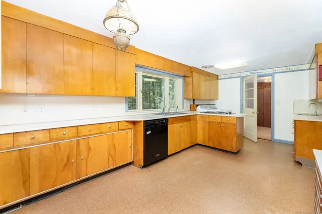 a large kitchen with stainless steel appliances granite countertop a sink dishwasher a refrigerator with wooden cabinets and floor