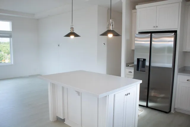 a kitchen with kitchen island white cabinets and refrigerator