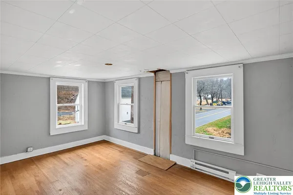a view of an empty room with window and wooden floor